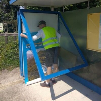 Pose affiche publicitaire par un employé de l'Atelier SIIS, entreprise qualifiée en prestation de services
