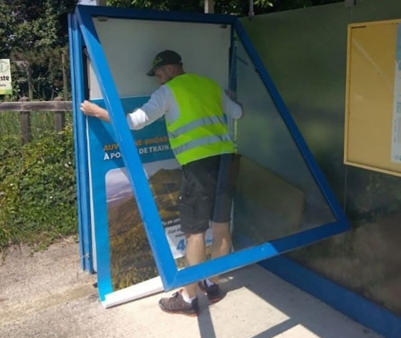 Pose affiche publicitaire par un employé de l'Atelier SIIS, entreprise qualifiée en prestation de services