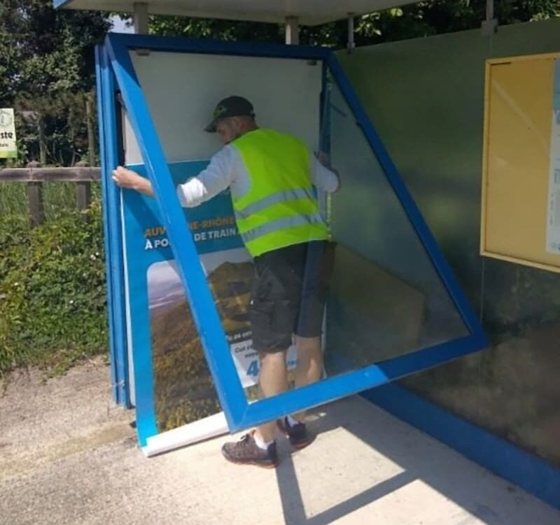 Pose affiche publicitaire par un employé de l'Atelier SIIS, entreprise qualifiée en prestation de services