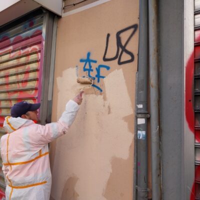 Nettoyage mobilier urbain par un employé de l'Atelier SIIS peignant sur un mur couvert de graffitis